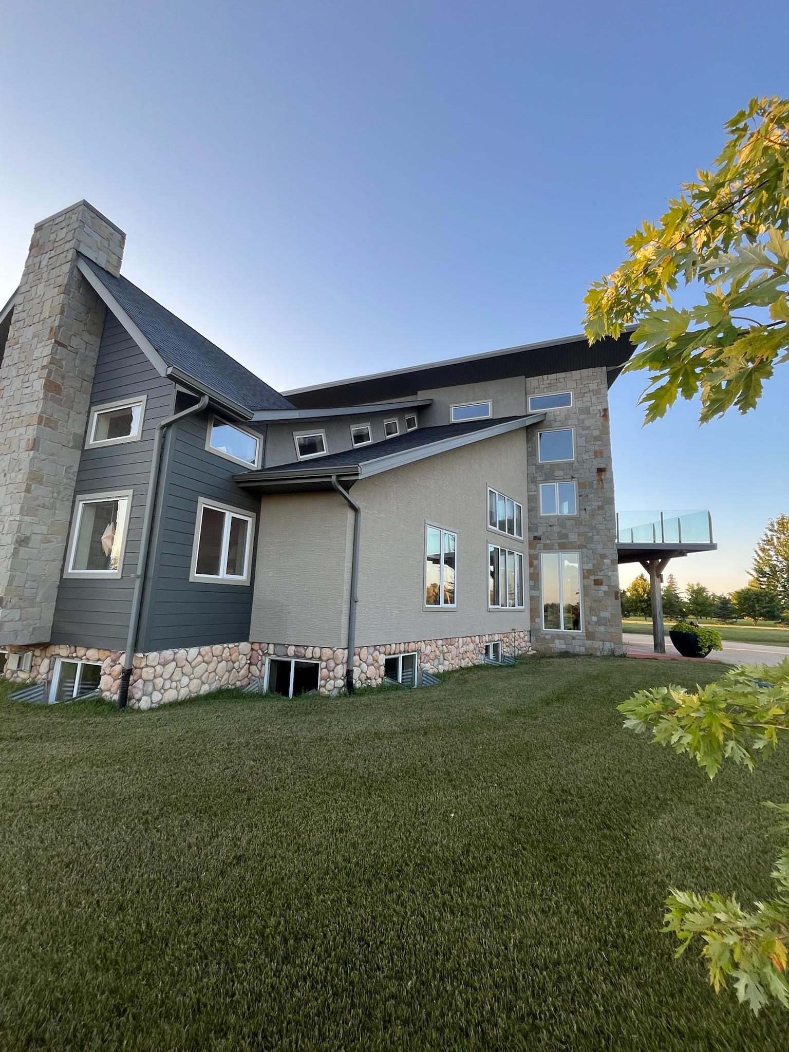 Exterior windows on a modern home with stone accents and a glass-railed balcony